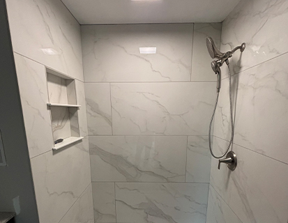 Walk-in shower with marble-look tile and built-in niche in a Westerville, OH bathroom remodel
